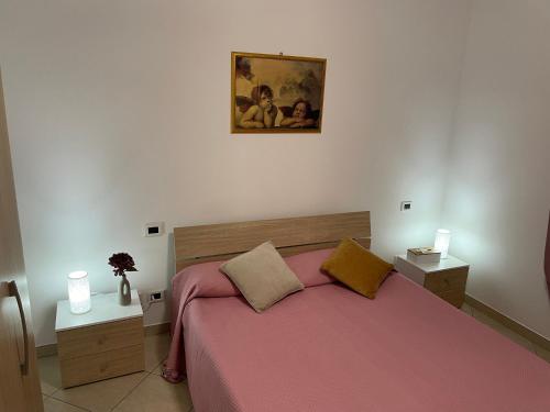 a bedroom with a bed with a pink bedspread and two tables at casa vacanza Cavour in Avezzano