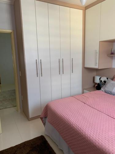 a bedroom with a pink bed and white cabinets at Casa Angélica in Guarulhos
