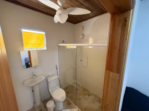 a bathroom with a toilet and a glass shower at Suítes Pitangueiras - POUSADA FRENTE MAR in Guarujá