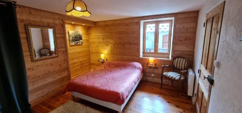 a bedroom with a red bed in a wooden room at La Frisanfave, Maison de village, centre 65M2 in Abriès