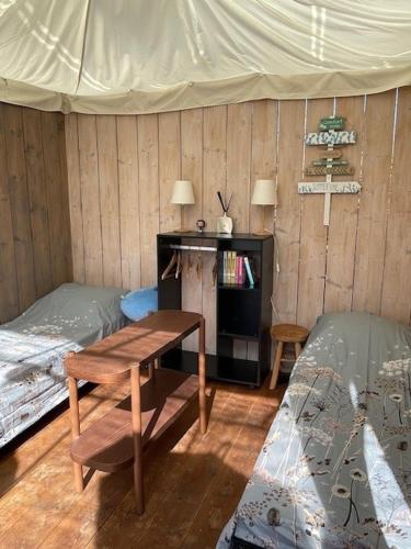 a room with two beds and a table and a cross at Vrijstaande accommodatie Glamping de Kas InN in Hank