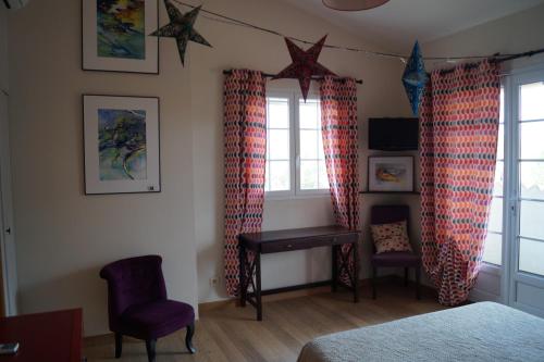 a bedroom with red curtains and a desk and two windows at appartement dans villa aquarelle in Biguglia