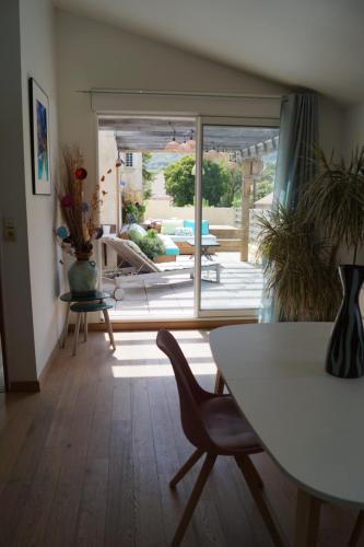 a living room with a table and a view of a patio at appartement dans villa aquarelle in Biguglia
