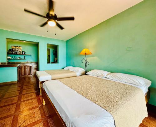 two beds in a room with a ceiling fan at Lake Arenal Hotel & Brewery in Tilarán