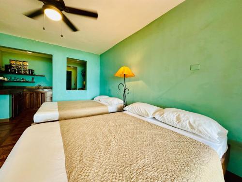 two beds in a room with a ceiling fan at Lake Arenal Hotel & Brewery in Tilarán