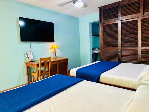 a bedroom with two beds and a desk with a television at Lake Arenal Hotel & Brewery in Tilarán
