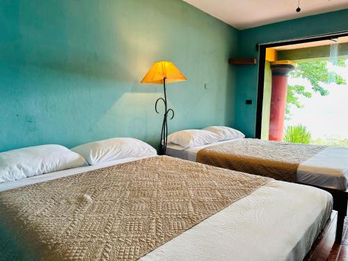 a room with three beds and a lamp in it at Lake Arenal Hotel & Brewery in Tilarán