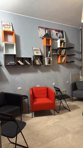 a living room with a red chair and chairs at Lion University & Youth Hostel Milano in Milan