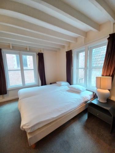 a bedroom with a large white bed with windows at Koffieboontje Budget in Bruges