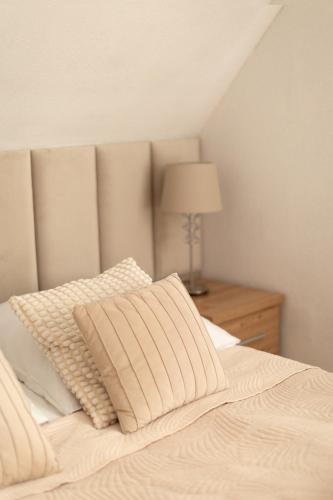 a bed with a pillow and a lamp on a table at APARTAMENTY VILLA PIGMALION - sauna, jacuzzi, parking, ogród in Kudowa-Zdrój