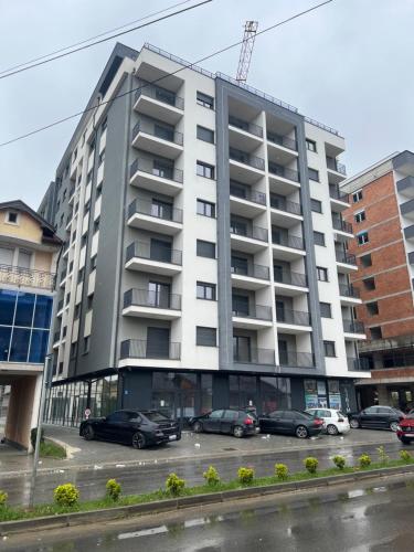 a large apartment building with cars parked in a parking lot at Liam Apartament in Prizren