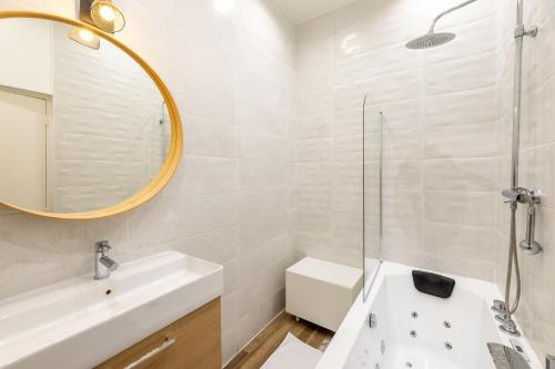 une salle de bain blanche avec un lavabo et un miroir dans l'établissement Escapade de Lyon, Relax & Balnéo Métro Charpennes, à Villeurbanne