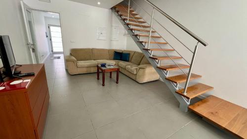 a living room with a couch and a staircase at Amazing Blue House in Ribeira Grande