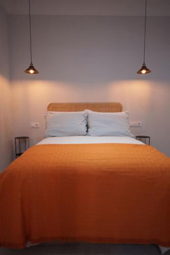 a bedroom with an orange bed with two lights at Apartamento Don Marcos A in Badajoz