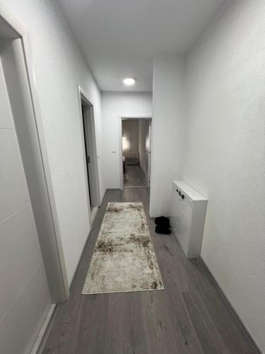 an empty hallway with a rug on a wooden floor at Liam Apartament in Prizren