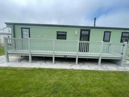 a green house with a porch and a bench at Fantasy Island, Sunnymede 8 Berth in Ingoldmells