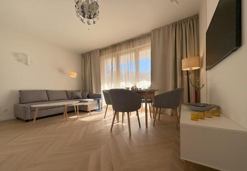 a living room with a table and chairs and a couch at Baltic Apartment White Diuna Supernovi in Gdynia
