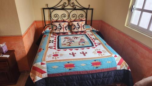 a bed with a quilt on it in a room at Casa Colonial Estate, Cozumel in Cozumel