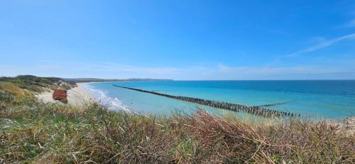 a view of a beach with the ocean in the background at Maison au calme avec jardin près du Château, forêt et plage in Condette