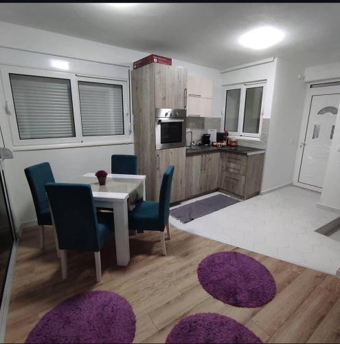 a kitchen with a table and blue chairs and a kitchen with a table at Mediterano Apartments in Ulcinj