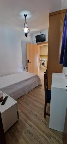 a bedroom with a bed and a table and a tv at Estalagem Soeiro Meireles, Unipessoal, LDA in Lagoaça