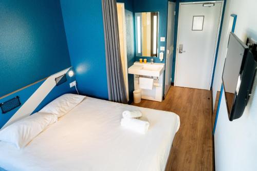 a blue room with a bed and a sink at ibis budget Aix en Provence in Aix-en-Provence