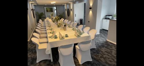 a long table with white chairs in a room at Berghotel Kristall in Idar-Oberstein