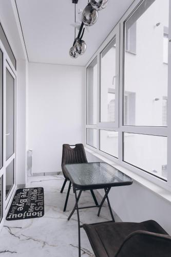 a living room with a table and chairs and windows at Apart Prokof'yeva in Sumy