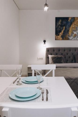 a white table with two plates and glasses on it at Apart Prokof'yeva in Sumy