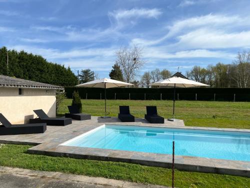 une piscine avec chaises et parasols dans l'établissement Maison avec piscine et étang, un coin de paradis, à Vendoeuvres