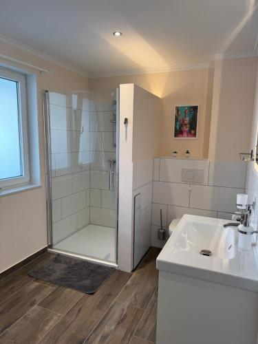 a white bathroom with a shower and a sink at Ferienhaus Maja in Kiel