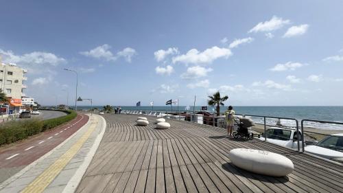 a boardwalk next to the ocean with people on it at Hills 2bdr Seaside Makenzy Larnaka in Larnaka