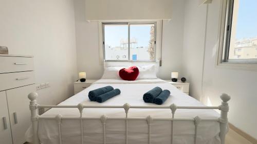a white bed with two pillows and a red heart on it at Hills 2bdr Seaside Makenzy Larnaka in Larnaka