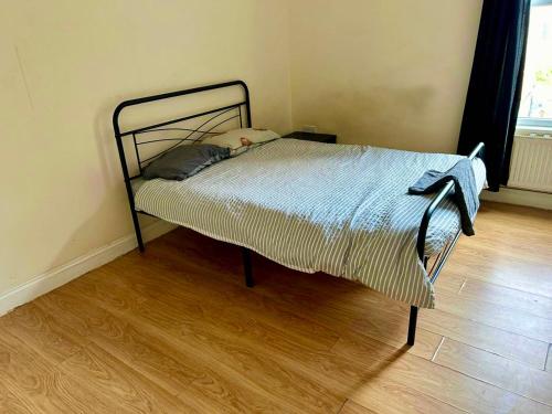 a bed in a room with a wooden floor at Thornton Heath in Thornton Heath