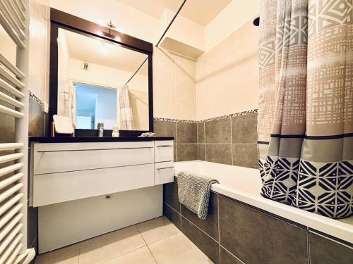 une salle de bain avec une baignoire, un lavabo et un miroir dans l'établissement Central 2 bed apartment in Antibes walk to beach & old town!, à Antibes