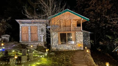 a house lit up at night with lights at Moksha By The River,Jibhi in Jibhi
