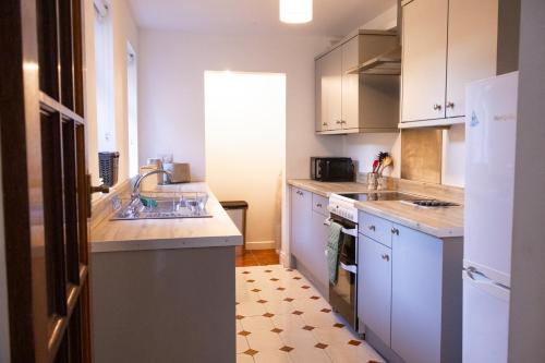 a kitchen with white cabinets and a sink at Victoria Road Guesthouse in Belfast