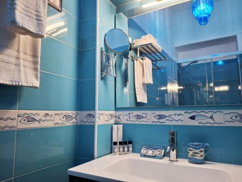 Un baño azul con lavabo y espejo. en Inn Alta Marea, en Salerno