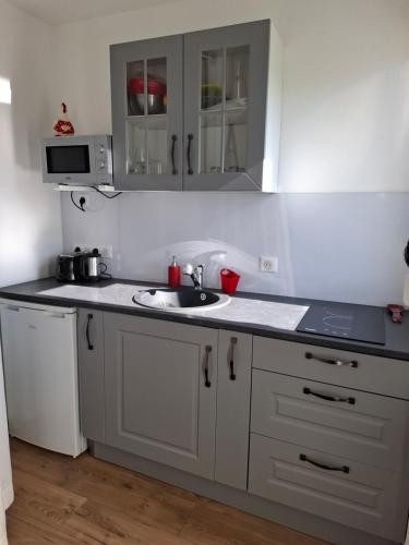 une cuisine avec des armoires blanches et un évier dans l'établissement Bienvenue chez Nous ! studio privé, parking, calme, à Rixheim