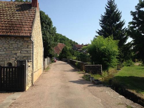 a dirt road next to a house with a tree at Longère du ruisseau in Armes