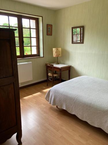 a bedroom with a bed and a desk with a lamp at Longère du ruisseau in Armes
