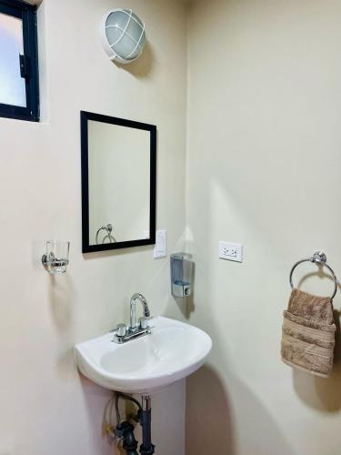 a white bathroom with a sink and a mirror at Posada Los Olivos in Loreto