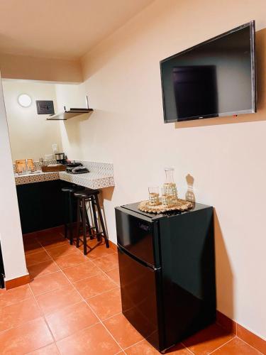 a kitchen with a black refrigerator with a flat screen tv on the wall at Posada Los Olivos in Loreto
