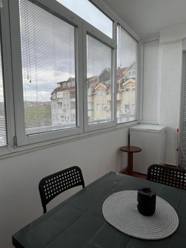 a dining room with a table and two chairs and two windows at Gabi's Cozy Corner in Kumanovo