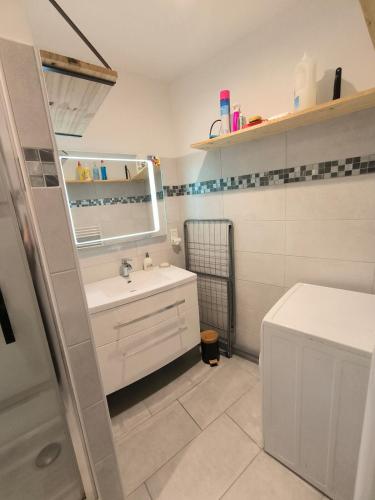 une salle de bain blanche avec un lavabo et un miroir dans l'établissement Charmante maison de village, à Suze-la-Rousse