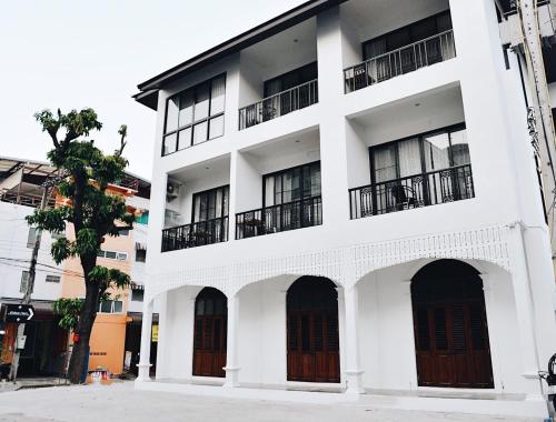 a white building with black doors and windows at OHDEE Hostel Chiangmai in Chiang Mai