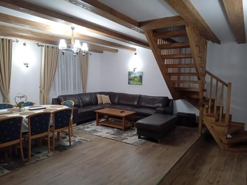 a living room with a black leather couch and a wooden staircase at Cabana Gura Voronețului in Gura Humorului