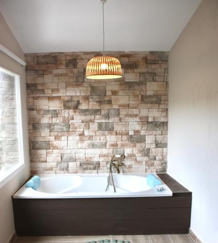 a bath tub in a bathroom with a brick wall at Finca Avellaneda Casa Completa in Navahondilla