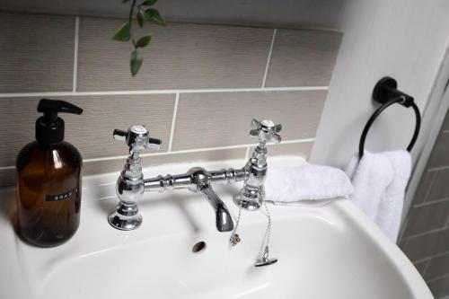 a white bathroom sink with a soap dispenser on it at Cosy, tranquil, fully equipped & beautiful garden - Dene Cottage in Newham