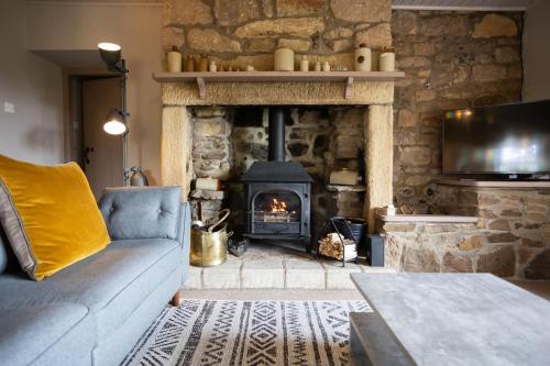 a living room with a stone fireplace and a couch at Cosy, tranquil, fully equipped & beautiful garden - Dene Cottage in Newham
